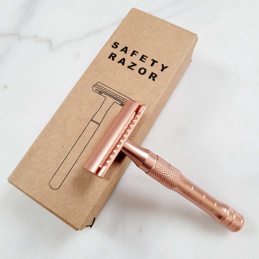 A rose gold double-edge safety razor resting on its packaging, crafted for zero-waste shaving and luxury self-care.