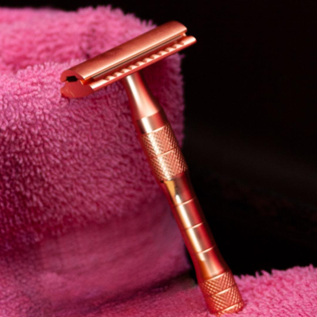 A rose gold safety razor propped on a soft pink towel, perfect for a luxurious, eco-friendly shaving routine.