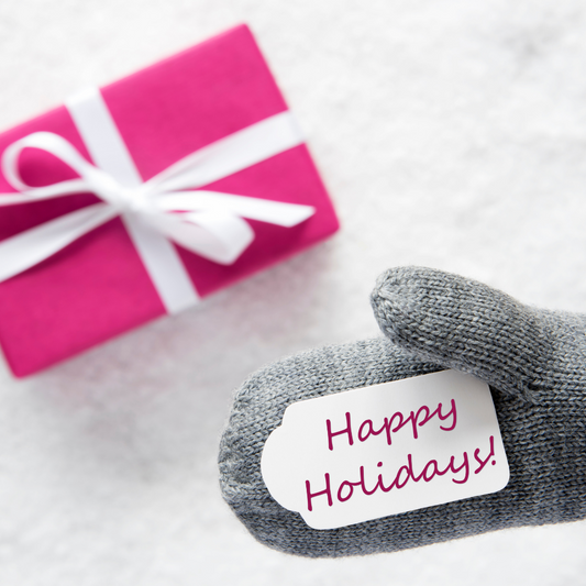 A note that says Happy Holidays on a grey mitten next to a pink present.