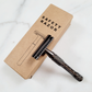 A matte black double-edge safety razor displayed on its box, offering a stylish, plastic-free alternative to disposable razors.