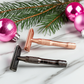 Safety razors in rose gold and matte black surrounded by festive holiday decorations, a thoughtful holiday gift for sustainable shaving and grooming.