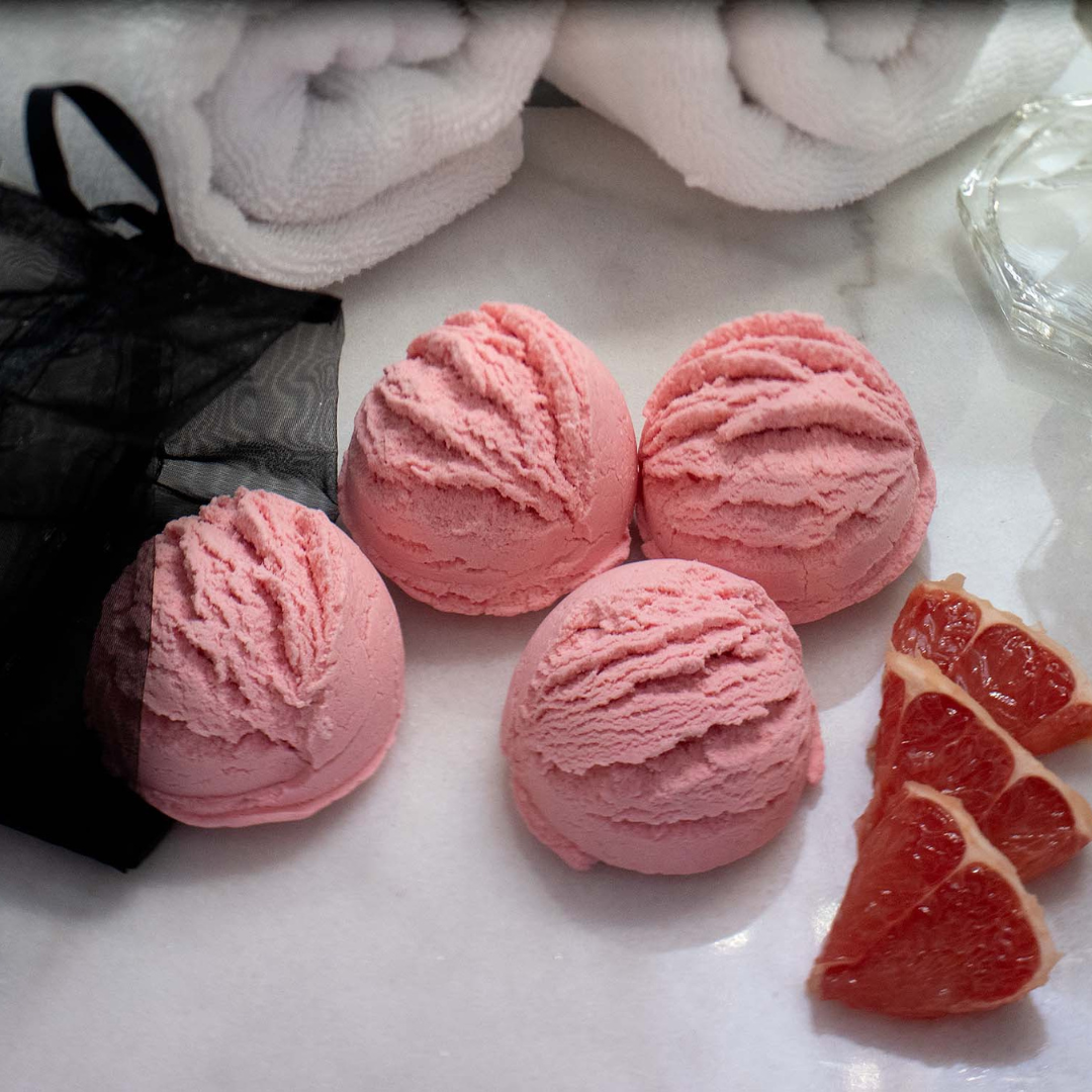4 Caley-Beth pink solid Bubble Bath Scoops, with a black organza bag and slices of grapefruit. 