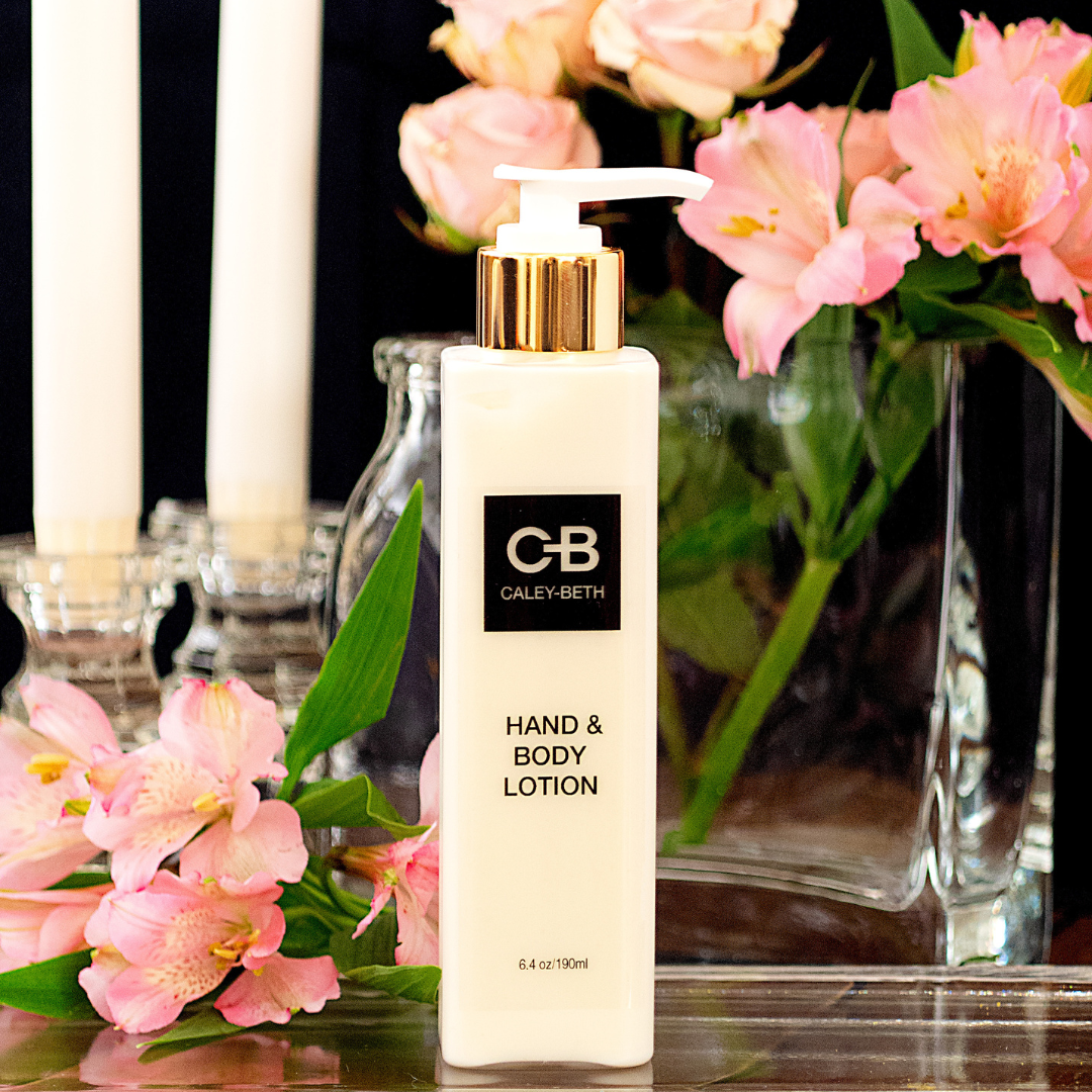 Caley-Beth Hand & Body Lotion surrounded by pink flowers and candles.