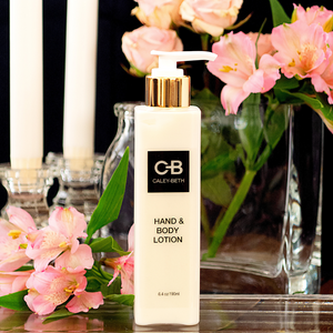 Open image in slideshow, Caley-Beth Hand &amp; Body Lotion surrounded by pink flowers and candles.
